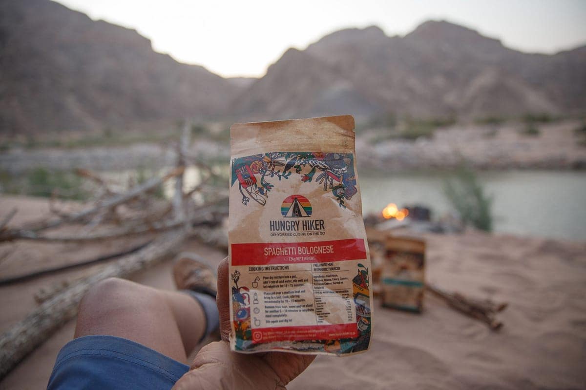 Hiker holding a Hungry Hiker meal pouch on the trail